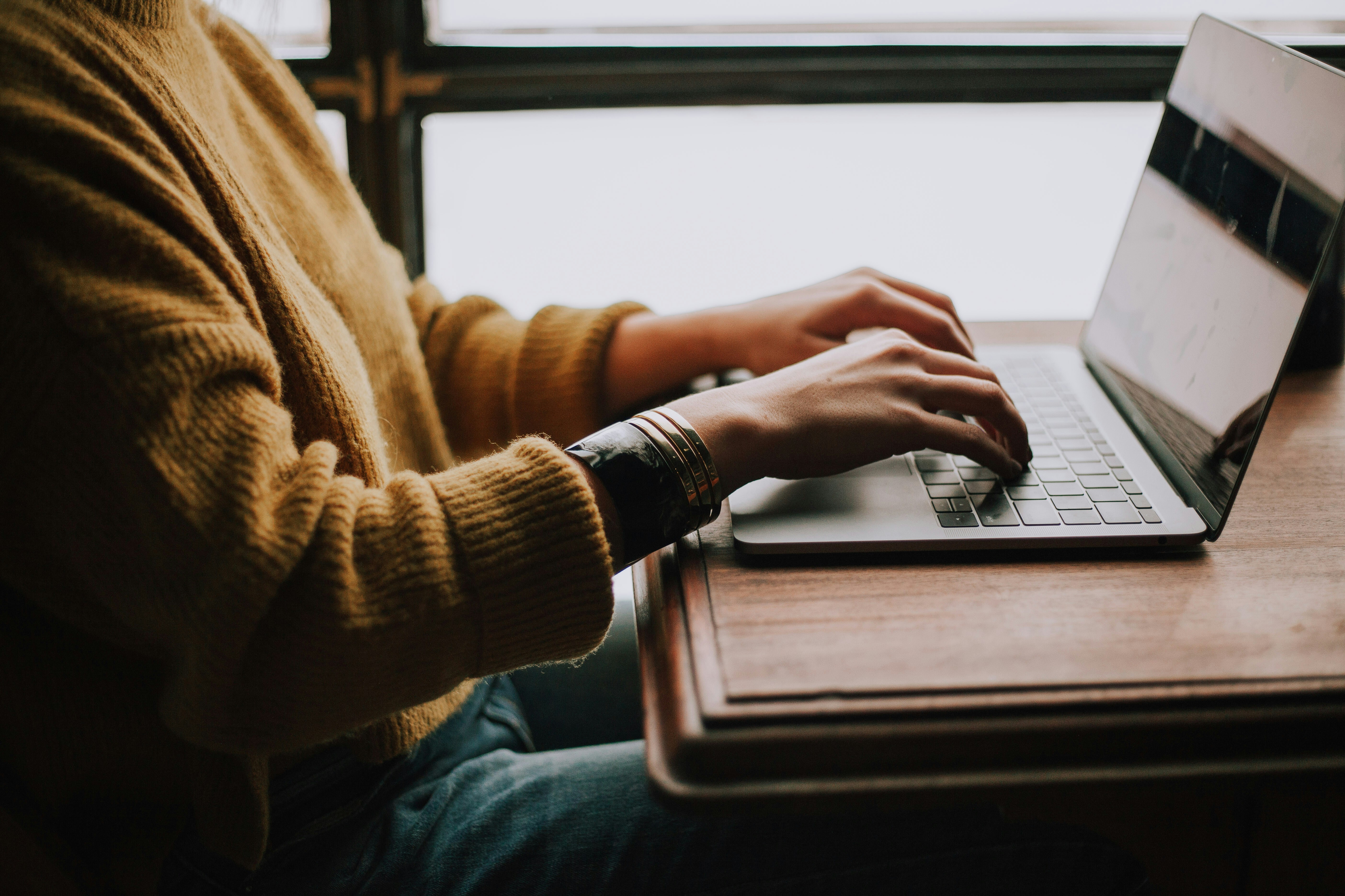 Person typing on a macbook while sitting down